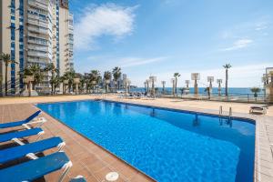 ベニドルムにあるSanta Margarita 15-E Apartment Levante Beachの海を背景にスイミングプール(椅子付)