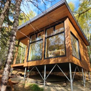 eine Hütte im Wald mit großen Fenstern in der Unterkunft Tanières MicroChalets Charlevoix in Baie-Saint-Paul