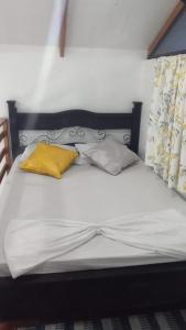 a white bed with two yellow pillows on it at LA CASITA DE PUEBLO NUEVO in Puerto Limón