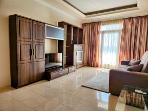 een woonkamer met een bank en een groot entertainmentcentrum bij Seafront Apartment - Wifi - Sleeps 6 - ChrisCourt in Marsaskala