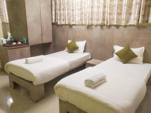2 Betten in einem kleinen Zimmer mit weißer Bettwäsche in der Unterkunft Le Green Kaziranga in Hatikhuli