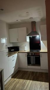 a kitchen with white cabinets and a black stove top oven at Stylish Media city Manchester apartment in Manchester