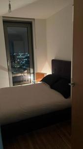 a bedroom with a bed and a window with a city at Stylish Media city Manchester apartment in Manchester
