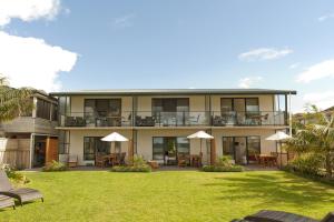 a building with a yard with chairs and umbrellas at Beachfront Resort in Whitianga