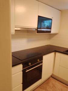 a kitchen with a microwave and a tv on the wall at koselig kjellerleilighet near sentrum in Moss