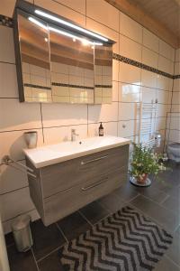 La salle de bains est pourvue d'un lavabo, d'un miroir et d'un tapis. dans l'établissement 4 Sterne Ferienwohnung Rabenlay, à Oberneisen