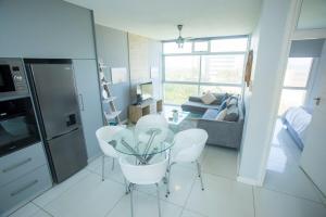 a kitchen with a table and white chairs in a room at Ballito Vacation Pad Ac Unit With Sea Views in Ballito