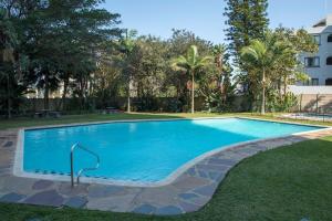 a swimming pool in a yard with trees and a building at Ballito Vacation Pad Ac Unit With Sea Views in Ballito