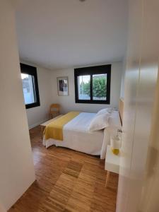 Un dormitorio con una cama blanca y dos ventanas. en O 3 de Monteferro, en Nigrán