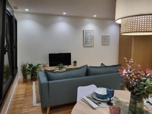 ein Wohnzimmer mit einem blauen Sofa und einem TV in der Unterkunft O 3 de Monteferro in Nigrán