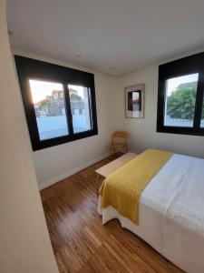 1 dormitorio con 2 ventanas, 1 cama y suelo de madera en O 3 de Monteferro, en Nigrán