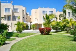 a large white house with palm trees and a lawn at EXCELENTE Depa en Acapulco Diamante FRENTE AL MAR! in Acapulco