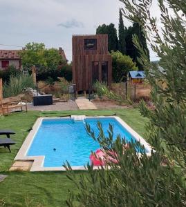 a swimming pool in a yard with a house at Maison de jardin 4 personnes in Montpeyroux