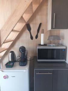 a kitchen with a microwave and utensils on the wall at Maison de jardin 4 personnes in Montpeyroux