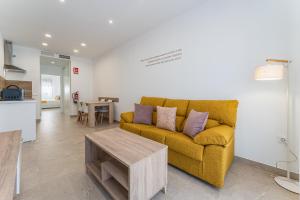 a living room with a yellow couch and a table at CMDreams Platinium- Apartamentos turísticos en el centro de Mérida in Mérida
