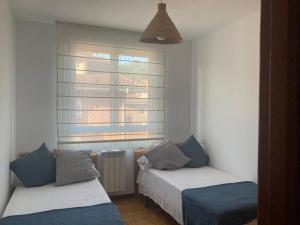 1 dormitorio con 2 camas y ventana en La Piragua, en Ribadesella