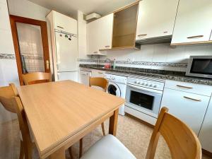 a kitchen with a table and a stove and a microwave at La Piragua in Ribadesella