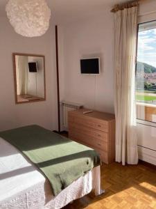 a bedroom with a bed and a dresser and a window at La Piragua in Ribadesella