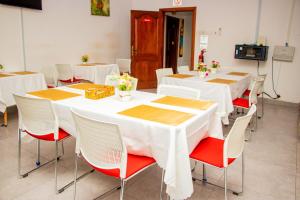 una sala de conferencias con mesas blancas y sillas rojas en Sweet Home Guest House, en Sogakofe