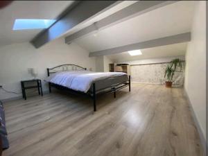 duża sypialnia z łóżkiem i drewnianą podłogą w obiekcie Maisonnette au calme avec parking w mieście Marguerittes