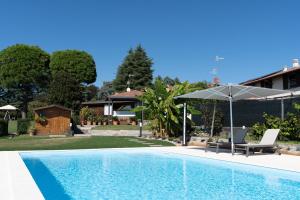 a swimming pool with an umbrella and a chair at Spina Verde Home in Como
