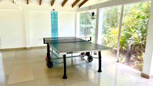 a ping pong table in a room with a large window at La Modestie Guest House in Grand'Anse Praslin
