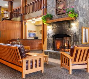 a living room with a stone fireplace and chairs at Grand Summit Hotel at Attitash in Bartlett