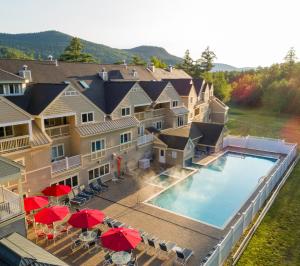 eine Luftansicht eines Hotels mit Pool und roten Sonnenschirmen in der Unterkunft Grand Summit Hotel at Attitash in Bartlett