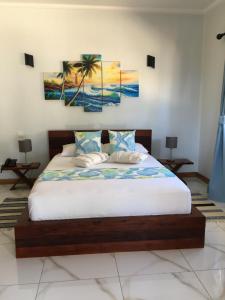 a bedroom with a bed with two paintings on the wall at Digwa Beach Chalet in La Digue
