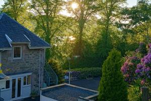 a house with a garden with flowers and trees at Peaceful and Stunning Waterside Location in Helensburgh