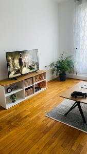 ein Wohnzimmer mit einem Flachbild-TV und Holzböden in der Unterkunft Appart hyper-centre, à 5 min à pieds de la gare in Longwy