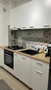 a kitchen with white cabinets and a black sink at Green Divine Apartament in Popeşti-Leordeni