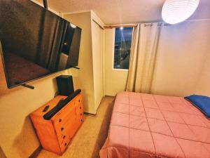 1 dormitorio con 1 cama y TV en la pared en Departamento Equipado Parejas, en Coquimbo