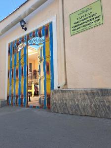 een winkel met een kleurrijke deur met een bord erop bij Tarallo Hotel in Bukhara
