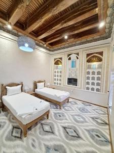 twee bedden in een kamer met een tapijt bij Tarallo Hotel in Bukhara
