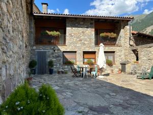 a stone house with a patio with a table and chairs at Turismo Rural Casa Sastre in Forcat