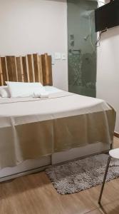 a bedroom with a bed with white sheets and a rug at Boutique Hotel Casa Teatro in Manaus