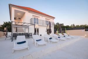 a group of chairs and umbrellas on a patio at Kuća za odmor Kamenjani-Škabrnja in Škabrnje