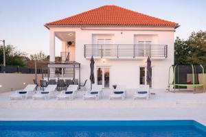 a villa with a pool and chairs and a house at Kuća za odmor Kamenjani-Škabrnja in Škabrnje