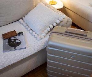 ein Koffer auf einem Bett neben einem Kissen in der Unterkunft Apartman Elle in Sombor