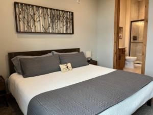 a bedroom with a large bed with blue and gray pillows at Brand New! Private hot tub, bunk room and walkable to restaurants/shops in Fraser