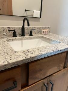 a bathroom sink with a granite counter top at Brand New! Private hot tub, bunk room and walkable to restaurants/shops in Fraser