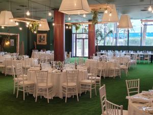une salle remplie de tables et de chaises avec un tissu de table blanc dans l'établissement Hotel Amaltea by Executive Sport, à Lorca