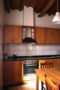 a kitchen with wooden cabinets and a wooden table with a wooden tableablish at Adega do Xelica - Holiday Cottage in Arcos