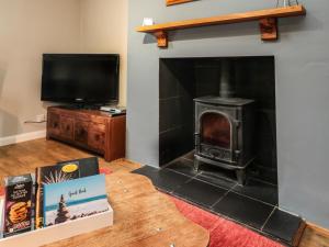 a living room with a wood stove and a tv at Maple Tree Cottage in Morpeth
