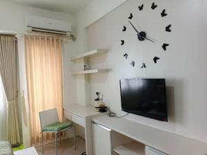 Zimmer mit einem TV und einem Schreibtisch mit einer Uhr an der Wand in der Unterkunft Studio Lavender Galeri Ciumbuleuit 2 in Bandung