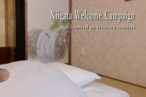een slaapkamer met een bed en een bord met Nigeriaanse welkomstcampagne beperkt tot bij YAKATA - Vacation STAY 58595v in Yuzawa