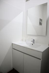 uma casa de banho branca com um lavatório e um espelho em Navio Azul Apartment no Funchal