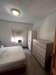 帕特納的住宿－Piso céntrico en Paterna，一间卧室配有一张床、一个梳妆台和一扇窗户。