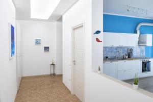a kitchen with white cabinets and a blue wall at Majú Home in Maiori